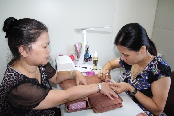 董紫羚(圖右)全神貫注幫客人做美甲服務 - 